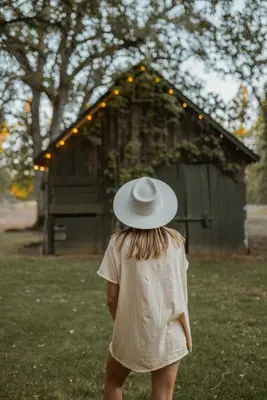 a woman wearing a hat standing in front of a building at Romantic Forest Lovers Nest by Casa Oso in Mariposa