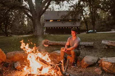 a man sitting next to a camp fire at Romantic Forest Lovers Nest by Casa Oso in Mariposa