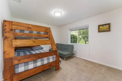 a bedroom with a bunk bed and a chair at Acorn House - Charming house in green heaven with pool table with lovely backyard in Oakhurst