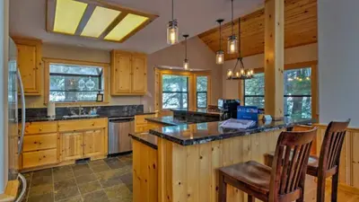 a large kitchen with wooden cabinets and a large island at Black Bear by AvantStay Spacious Viking Lodge in Tahoe Donner w Game Room Hot Tub in Truckee