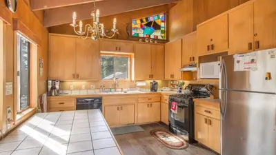 a kitchen with wooden cabinets and a stainless steel refrigerator at Mahogany by AvantStay Snowbird Cabin w Full Chamberlands Access in Homewood