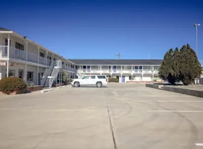 a white car parked in a parking lot in front of a building at American Inn in Hawthorne
