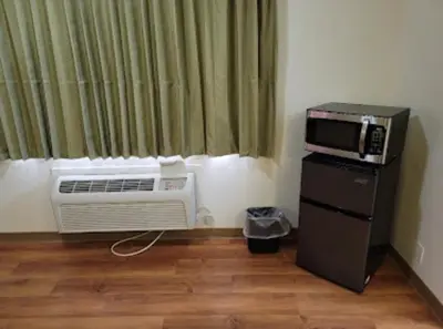 a room with a air conditioner and a microwave at American Inn in Hawthorne
