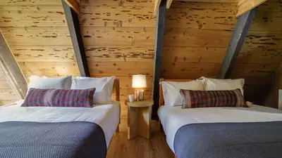 two beds in a room with wooden walls at Horizon by AvantStay Stunning A-frame Cabin w Hot Tub Billiards Lake Views in Tahoe City