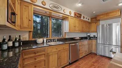 a kitchen with wooden cabinets and a stainless steel refrigerator at Ellis Peak by AvantStay Beautiful McKinney Cabin w Filtered Lake Views in Homewood