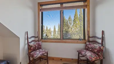 two chairs in front of a window with trees at Ellis Peak by AvantStay Beautiful McKinney Cabin w Filtered Lake Views in Homewood
