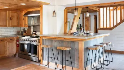 a kitchen with wooden cabinets and a counter with stools at Timberline by AvantStay Stunning Chalet Cabin w Hot Tub Pool Table Home Theater in Tahoe Vista