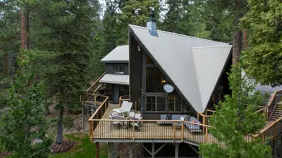a house in the woods with a wrap around deck at Timberline by AvantStay Stunning Chalet Cabin w Hot Tub Pool Table Home Theater in Tahoe Vista