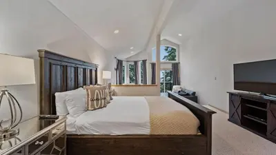 a bedroom with a large bed and a flat screen tv at Sparrow by AvantStay Modern Mountain Retreat w Hot Tub Pool Table Games in Truckee