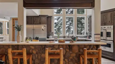 a kitchen with a large stone counter top and wooden cabinets at Sparrow by AvantStay Modern Mountain Retreat w Hot Tub Pool Table Games in Truckee