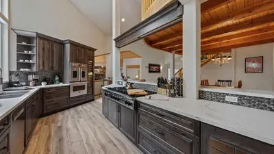 a large kitchen with wooden cabinets and wooden floors at Sparrow by AvantStay Modern Mountain Retreat w Hot Tub Pool Table Games in Truckee