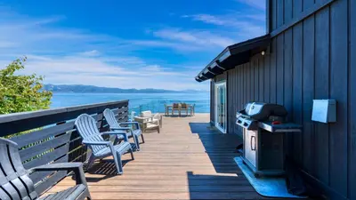 a deck with chairs and a grill on the side of a house at Lakeview by AvantStay Private Waterfront Cabin on Lake Tahoe w Hot Tub Views in Tahoe Vista