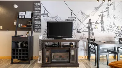 a living room with a tv on a stand with a table at Flurry by AvantStay Tahoe Donner Home w Access to Northstar Resort Community in Kingswood Estates
