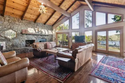 a living room with leather furniture and a stone wall at Dos Pinos Spacious Lakefront Cabin with Game Room in Groveland