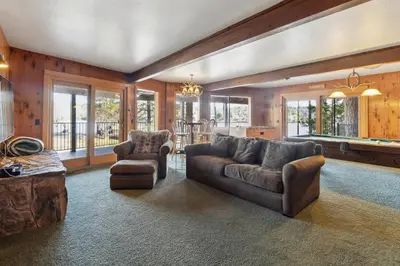 a living room with a couch and chairs and windows at Dos Pinos Spacious Lakefront Cabin with Game Room in Groveland