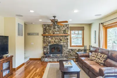 a living room with a couch and a stone fireplace at Better at the Lake Home with Private Dock in Groveland