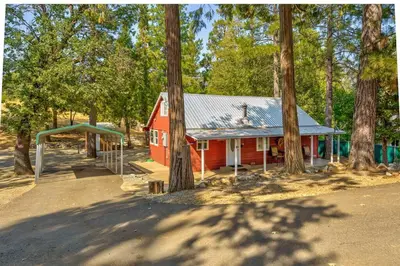 a red barn with a playground next to trees at Acorn Cabin - Charming Place, Your getaway to Yosemite, Bass Lake in Oakhurst