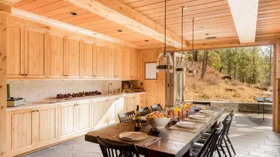 a large kitchen with a long wooden table and chairs at Hunter by AvantStay Award-Winning Riverfront Cabin 5 Minutes from Palisades in Olympic Valley