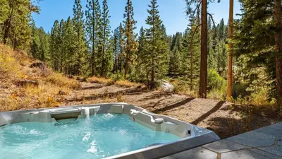 a hot tub in the middle of a forest at Hunter by AvantStay Award-Winning Riverfront Cabin 5 Minutes from Palisades in Olympic Valley