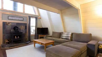 a living room with a couch and a fireplace at Zephyr by AvantStay Stylish Modified A Frame w Access To Tahoe Donner in Truckee
