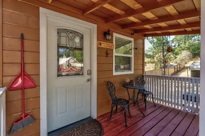 a front door of a house with a table and chairs at Acorn Cottage - Hidden gem in green heaven, getaway to Bass Lake & Yosemite in Oakhurst