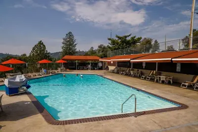 a large swimming pool with tables and umbrellas at Pet Friendly The Hideout Yosemite Home in Groveland