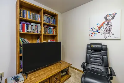 a living room with a tv and a book shelf at Miner's Claim - Home with 2 Decks & Pool in Groveland