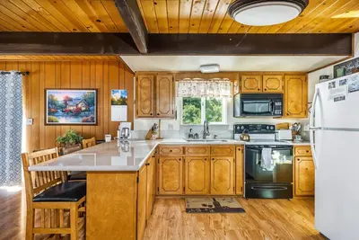a kitchen with wooden cabinets and a white refrigerator at Lakefront Cozy Cabin on the Cove in Groveland