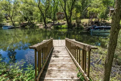 a wooden bridge over a river with a boat at Lakefront Cozy Cabin on the Cove in Groveland