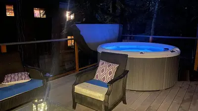 a hot tub sitting on a deck with a chair at Sweet Pine Deck Hot Tub Cozy Modern Interior Close to Ski Resort in Pomins