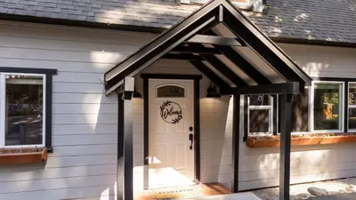 a house with a white door with a black roof at Sweet Pine Deck Hot Tub Cozy Modern Interior Close to Ski Resort in Pomins