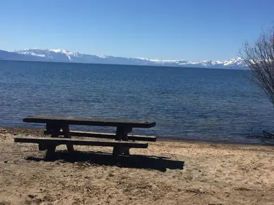 a picnic table sitting on the shore of a lake at Lakeside Hotel room #7 in Kings Beach in Kings Beach