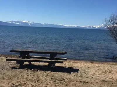 a picnic table sitting on the shore of a lake at Lakeside hotel room #8 in Kings Beach in Kings Beach