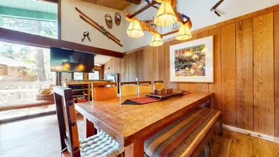 a dining room with a wooden table and a television at Chateau Sans Nom #19 condo in Mammoth Lakes