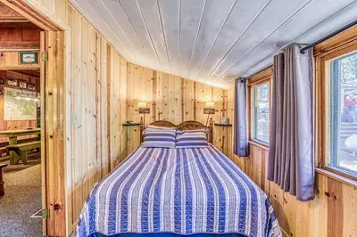 a bedroom with a bed in a room with wooden walls at Alpine Cottage in Shaver Lake