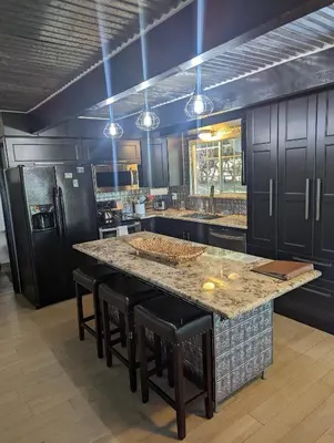 a kitchen with black cabinets and a large island with bar stools at Breckenridge Chalet near Yosemite. Dog friendly! in Groveland