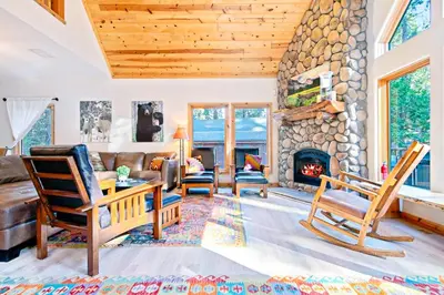 a living room with a stone fireplace and chairs at Oso Lodge in Yosemite West