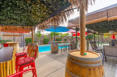 a patio with a table and chairs and a palm tree at Tropical Paradise in Fresno