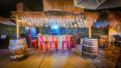 a bar with red chairs and a table and barrels at Tropical Paradise in Fresno