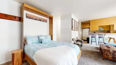a bedroom with a large bed and a kitchen at La Vista Blanc #59 condo in Mammoth Lakes