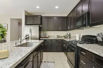 a kitchen with black cabinets and a stainless steel refrigerator at Stunning River Islands Home Near Lake & Boat House in Lathrop