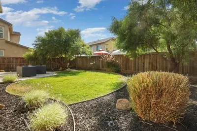 a backyard with a fence and a yard with grass at Stunning River Islands Home Near Lake & Boat House in Lathrop