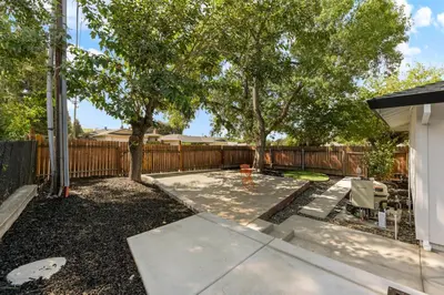 a backyard with a fence and a tree at Fully Renovated 4 Bedroom Home with Pool! in Roseville