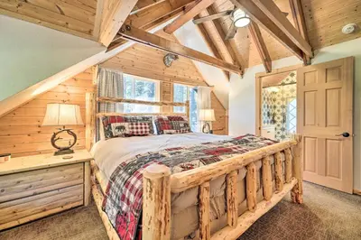 a bedroom with a wooden bed and a window at Waterfront Echo Lake Cabin with Deck, Mtn Views in Twin Bridges