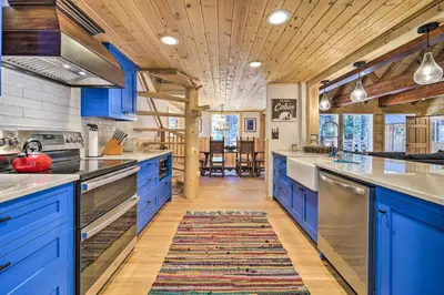 a kitchen with blue cabinets and a wooden ceiling at Waterfront Echo Lake Cabin with Deck, Mtn Views in Twin Bridges
