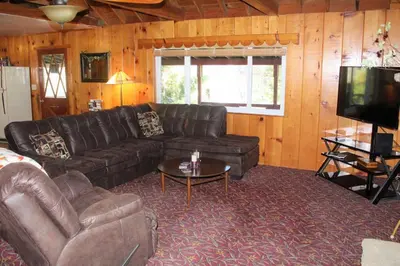 a living room with a leather couch and a television at Rustic Chapparal Cabin at Bass Lake Heights in Oakhurst