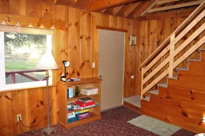 a room with wooden walls and a staircase and a lamp at Rustic Chapparal Cabin at Bass Lake Heights in Oakhurst