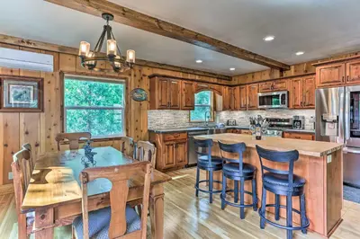 a kitchen with wooden cabinets and a large island with bar stools at Rustic Oakhurst Retreat Less Than 4 Mi to Bass Lake! in Oakhurst