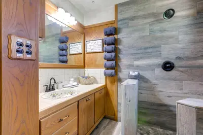 a bathroom with a sink and a wooden wall at 1 Mi to Lake Hot Tub Haven in Pollock Pines! in Pollock Pines
