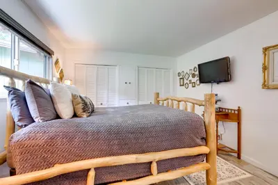 a bedroom with a wooden bed and a flat screen tv at 1 Mi to Lake Hot Tub Haven in Pollock Pines! in Pollock Pines